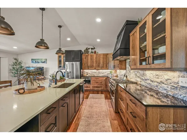 a kitchen with stainless steel appliances granite countertop a sink a stove and a wooden floors