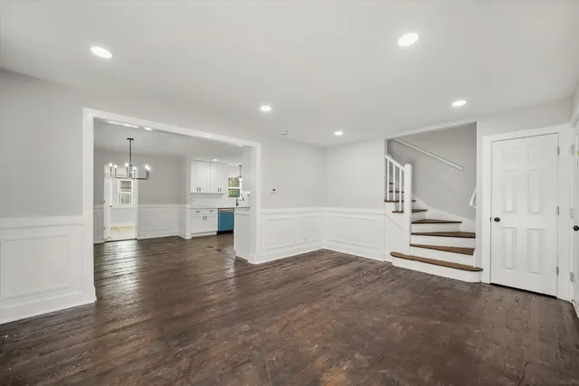 a view of an empty room with wooden floor and stairs