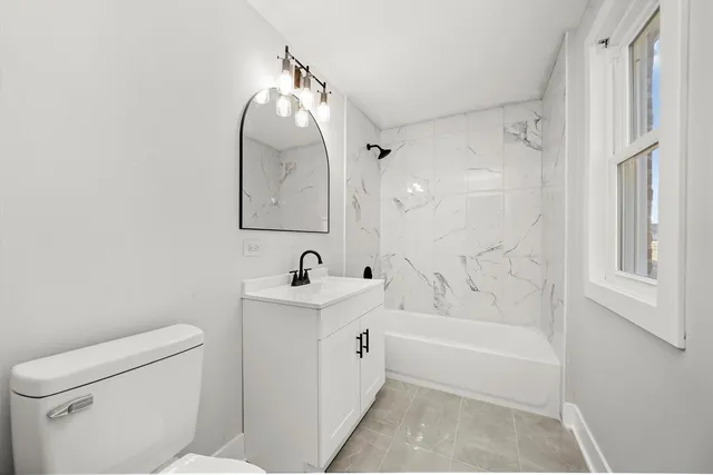 a spacious bathroom with a tub sink toilet and a mirror