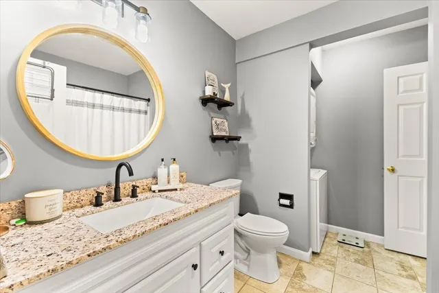 a bathroom with a granite countertop toilet a sink and a mirror