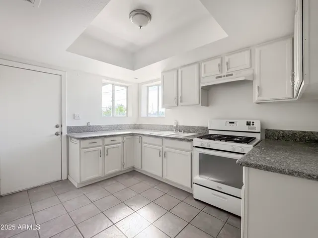a kitchen with white cabinets appliances and a window
