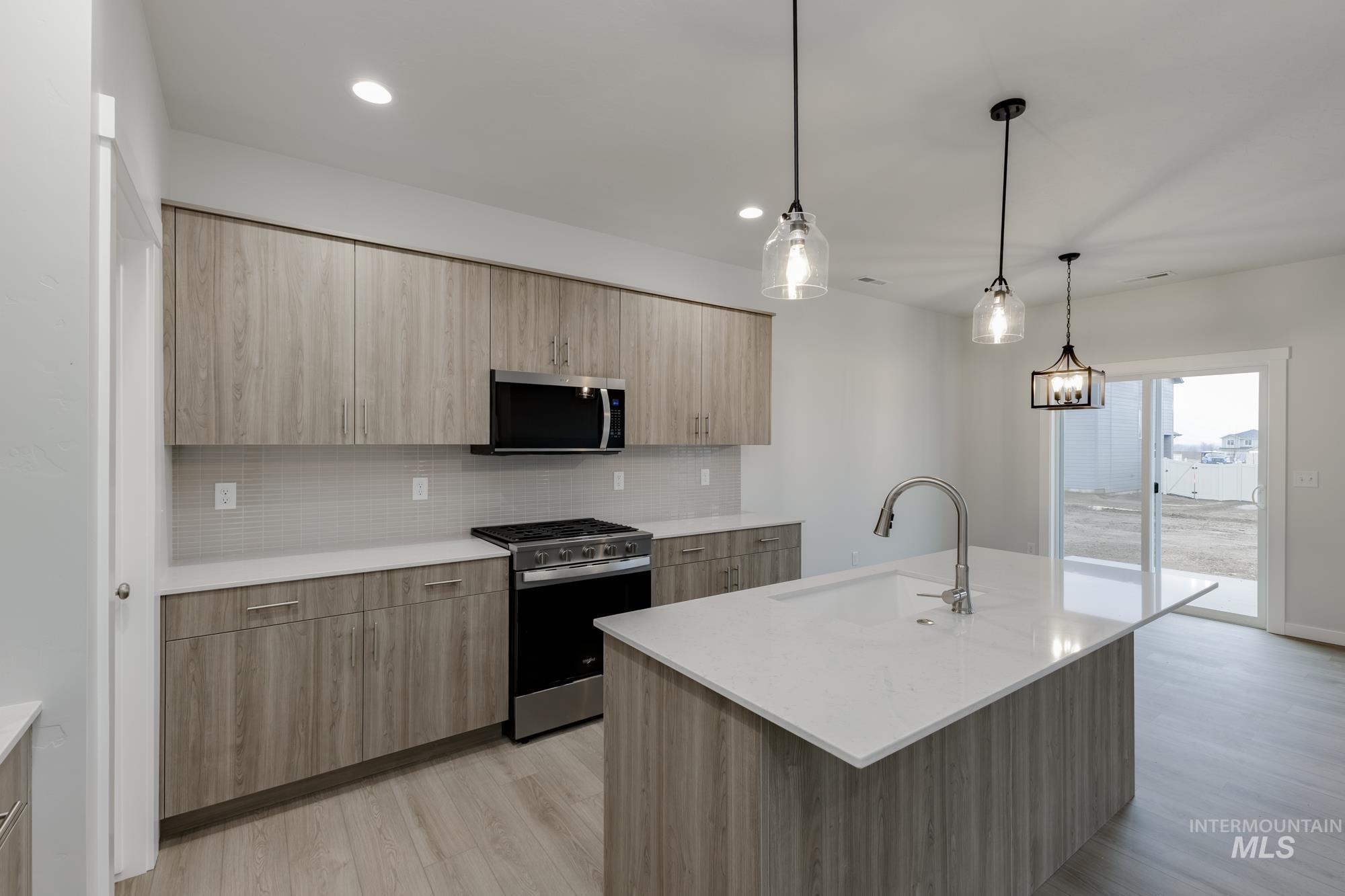 2086 South Border Way Meridian, ID 83642 - Photo 3 of 19 Kitchen with modern cabinets, stainless steel appliances, pendant lighting, light wood-type flooring, and light stone counters