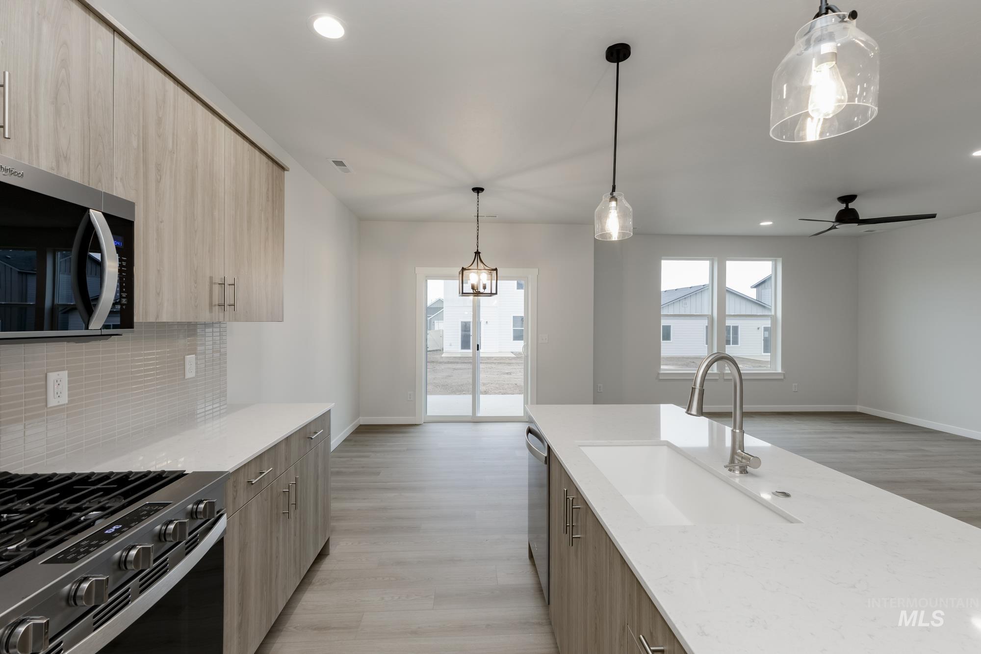 2086 South Border Way Meridian, ID 83642 - Photo 4 of 19 Kitchen featuring two tone cabinets, hanging light fixtures, modern cabinets, stainless steel appliances, and light stone countertops