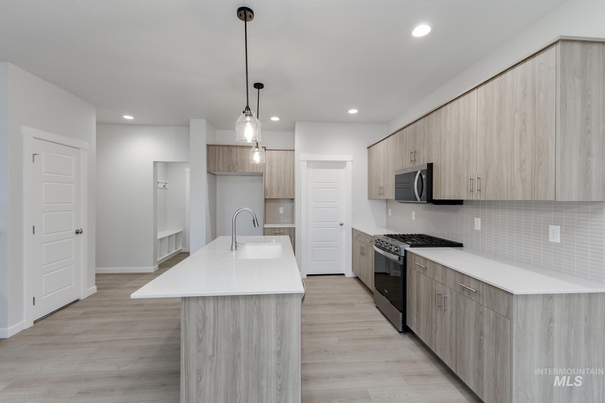 2086 South Border Way Meridian, ID 83642 - Photo 5 of 19 Kitchen featuring light stone countertops, modern cabinets, light wood finish cabinets, stainless steel appliances, and hanging light fixtures