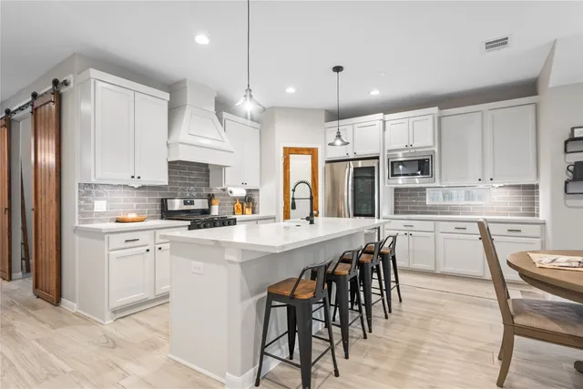 a kitchen with kitchen island granite countertop wooden floors white cabinets and appliances