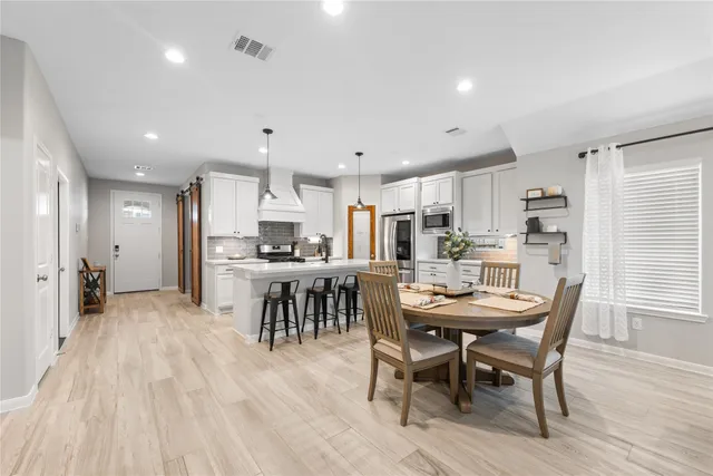 a dining area with stainless steel appliances kitchen island granite countertop a dining table chairs and view kitchen