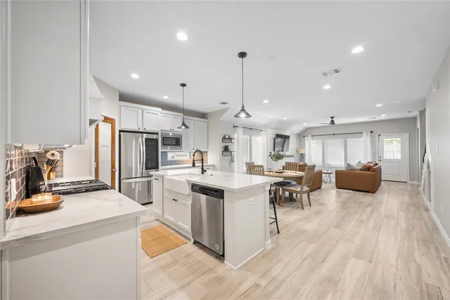 a kitchen with stainless steel appliances kitchen island granite countertop a sink and a refrigerator
