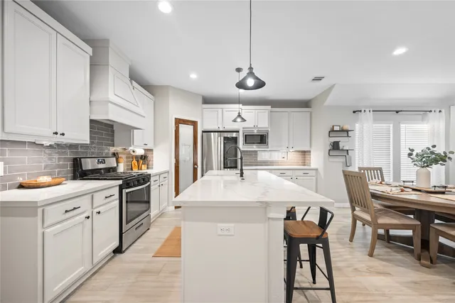 a large kitchen with lots of counter space a sink appliances and a dining table
