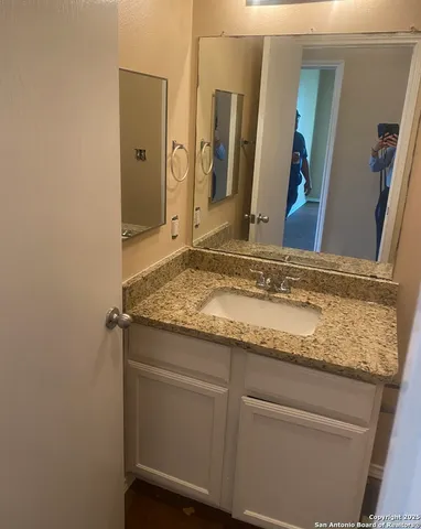 a bathroom with a granite countertop sink and a mirror