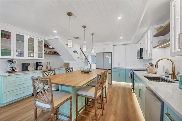 a kitchen with stainless steel appliances kitchen island a table chairs in it and wooden floors