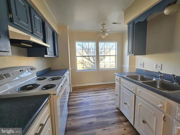a kitchen that has a sink a stove and wooden floor