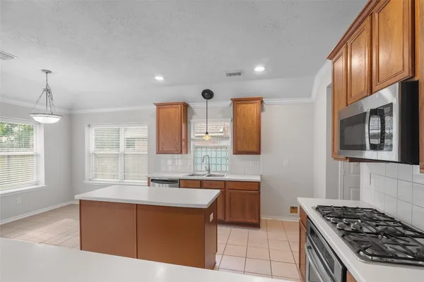 a large kitchen with stainless steel appliances granite countertop a stove top oven a sink dishwasher and white cabinets next to a window