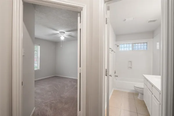 an empty room with chandelier fan and windows