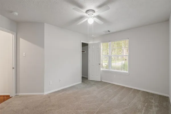 an empty room with windows and fan