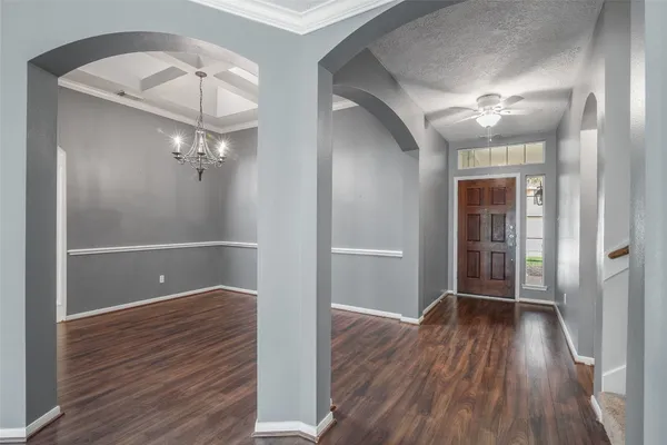 an empty room with wooden floor chandelier and entryway