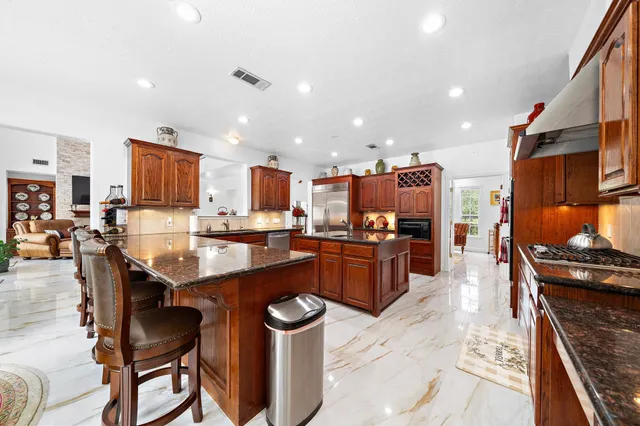 a kitchen with stainless steel appliances kitchen island granite countertop a table chairs sink and cabinets