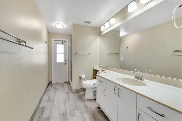 a spacious bathroom with a double vanity sink a toilet and a mirror