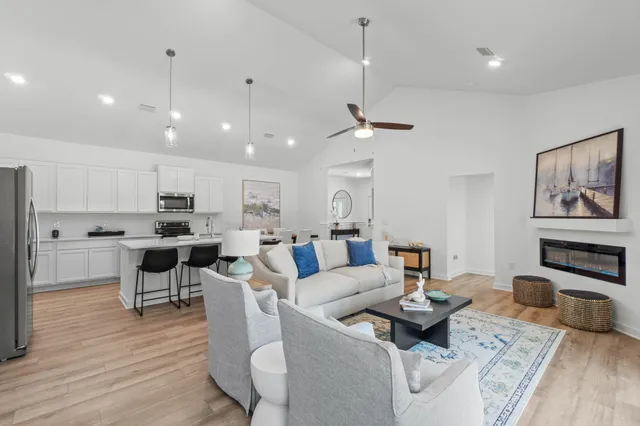 a living room with furniture kitchen view and a wooden floor