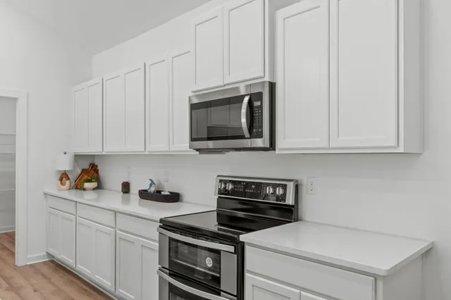 a kitchen with stainless steel appliances granite countertop white cabinets and a stove top oven