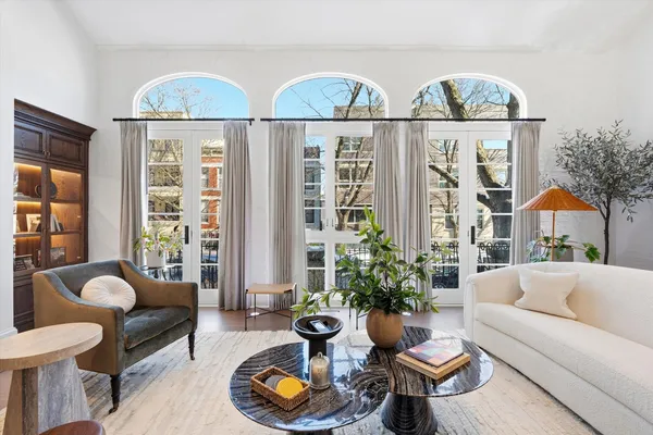 a large kitchen with stainless steel appliances kitchen island granite countertop a stove a sink a refrigerator white cabinets and couches with wooden floor