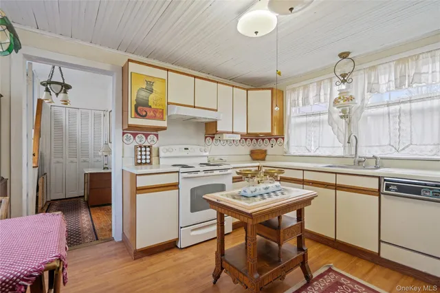 a kitchen with a sink a stove a refrigerator cabinets and dining table