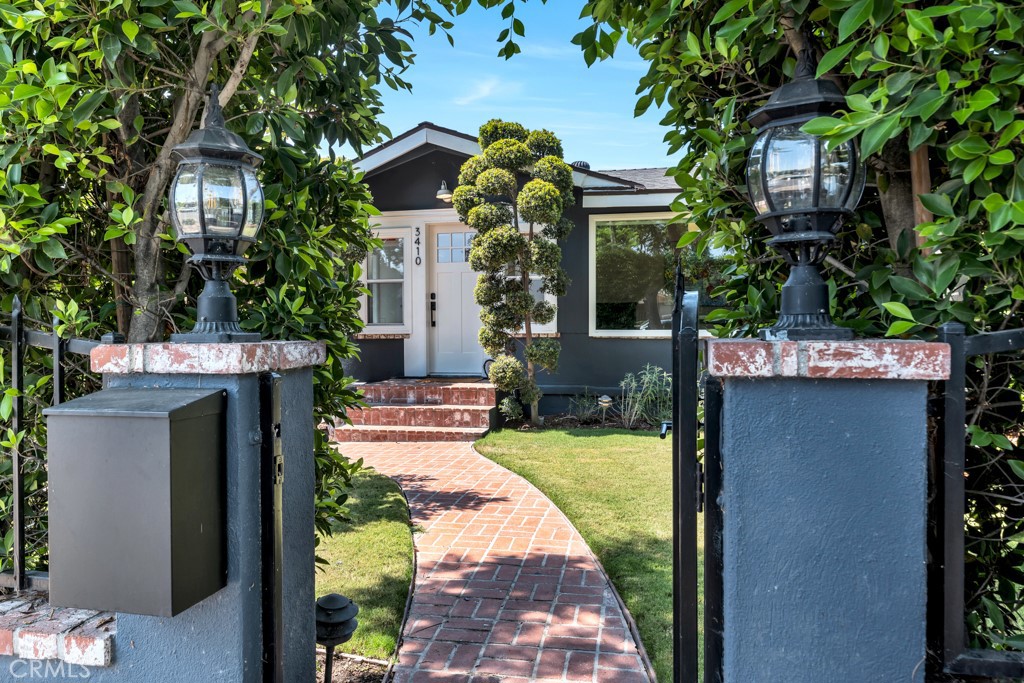 a view of a house with a small yard and large tree