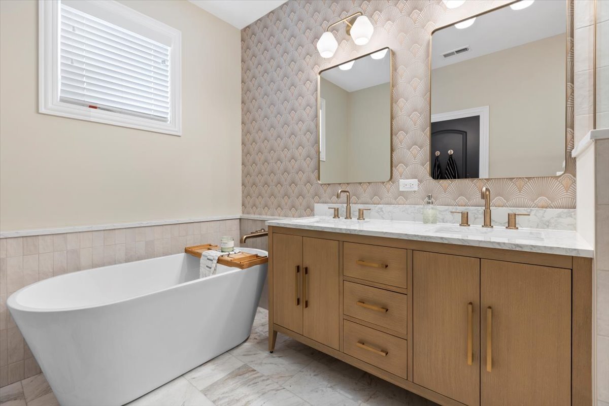 2463 West Foster Avenue, Unit 3 Chicago, IL 60625 - Photo 19 of 31 a bathroom with a double vanity sink large mirror and a bathtub