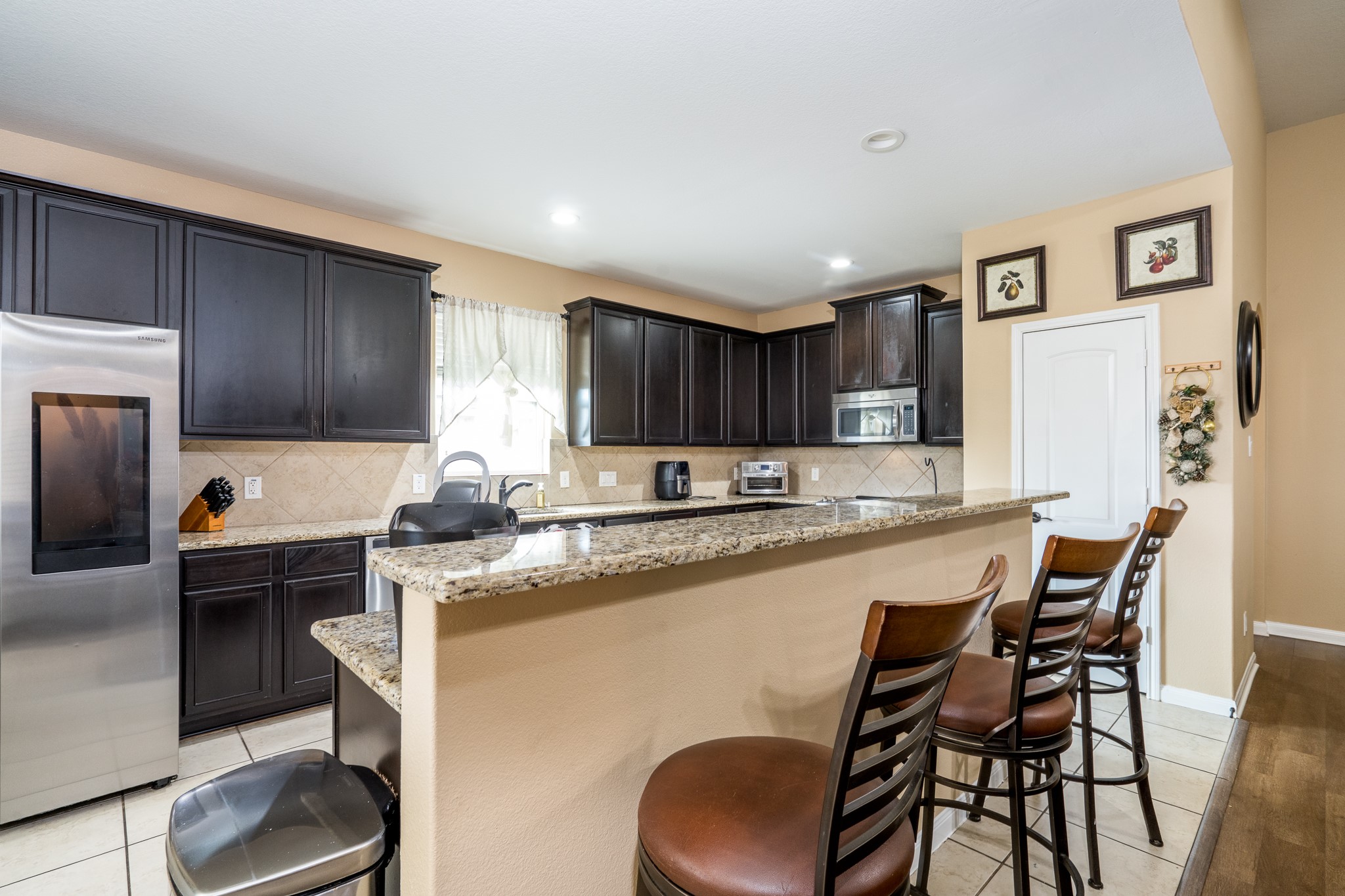 18879 Atascosa Trail Magnolia, TX 77355 - Photo 6 of 25 a kitchen with stainless steel appliances granite countertop a sink a stove a refrigerator cabinets and chairs