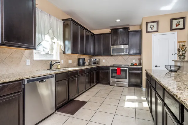 a kitchen with stainless steel appliances granite countertop a sink counter space cabinets and a window