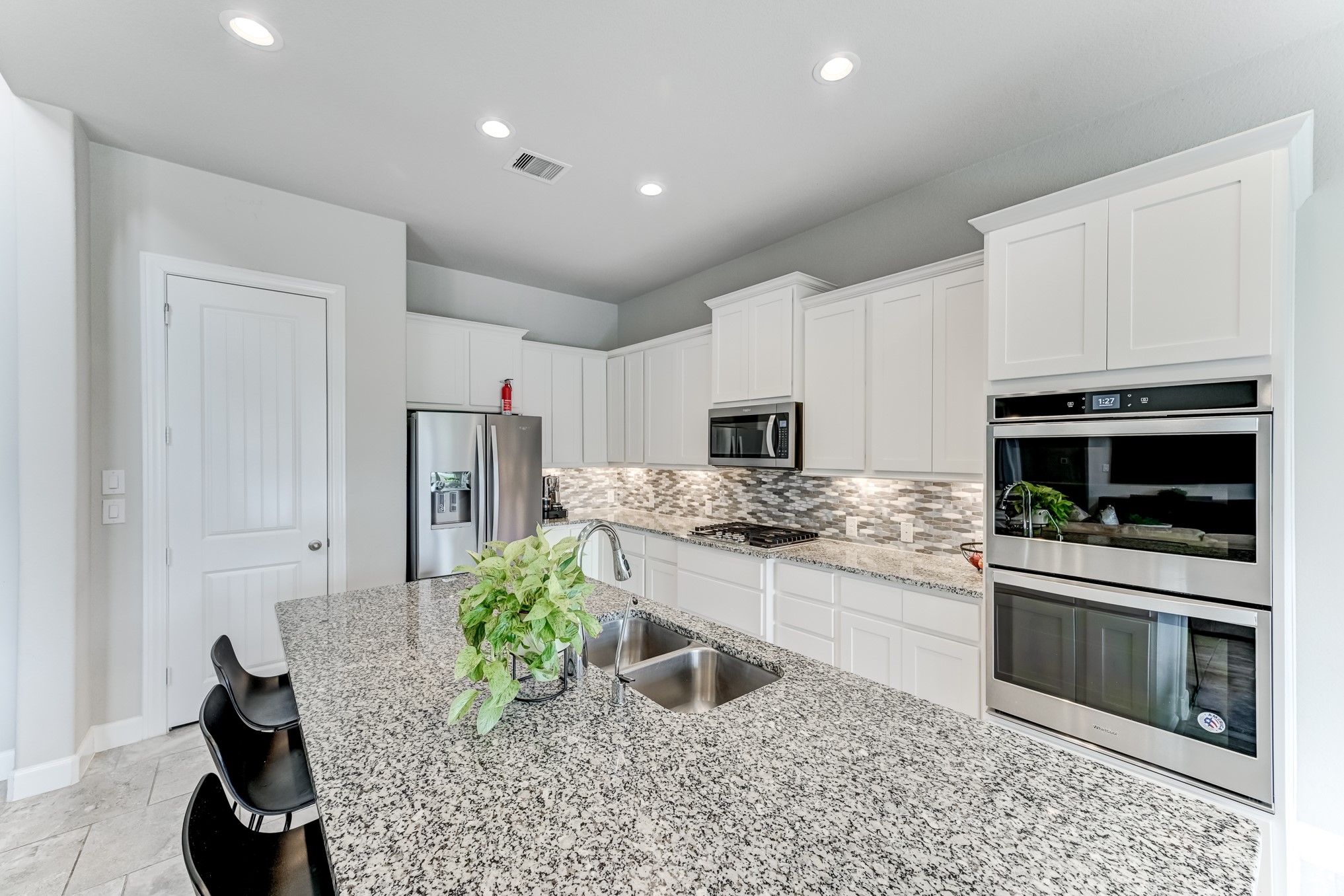 5806 Metaphor Way Rosenberg, TX 77469 - Photo 17 of 50 a kitchen with stainless steel appliances kitchen island granite countertop a stove a sink and a microwave