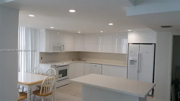 a kitchen with a sink a refrigerator and chairs
