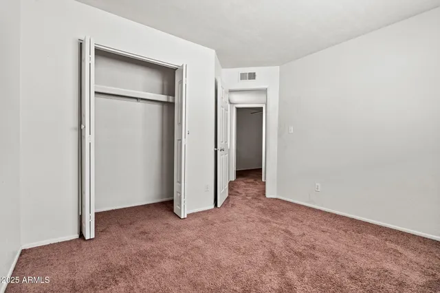 a view of an empty room with closet and a window