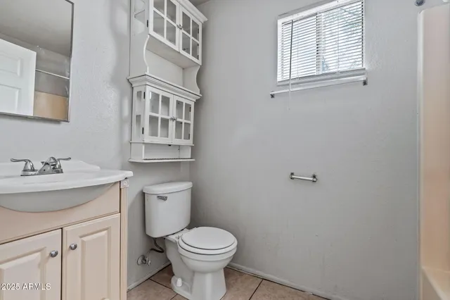 a bathroom with a granite countertop toilet a sink and a window