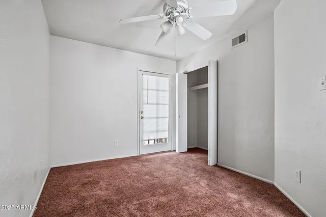 an empty room with a chandelier fan and closet