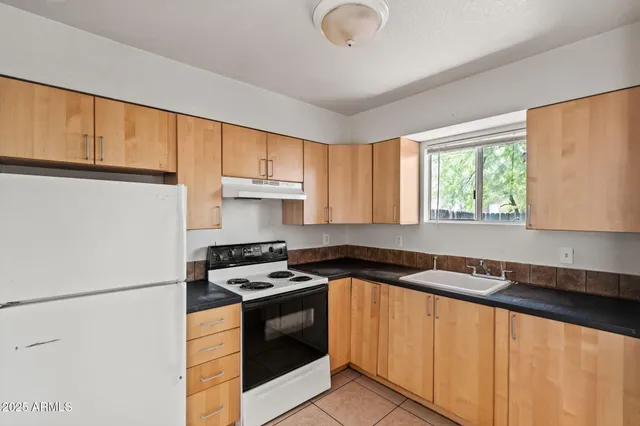 a kitchen with granite countertop a sink a stove cabinets and a refrigerator
