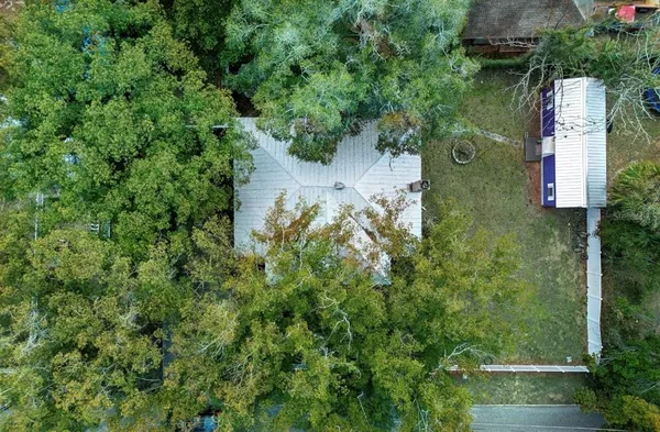 an aerial view of a house with a yard and large trees