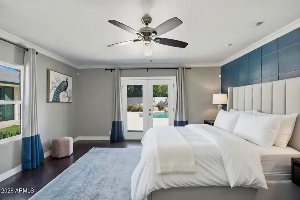 a bedroom with a large bed couch and two window