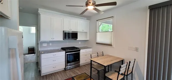 a kitchen with stainless steel appliances granite countertop a workspace chairs sink and cabinets