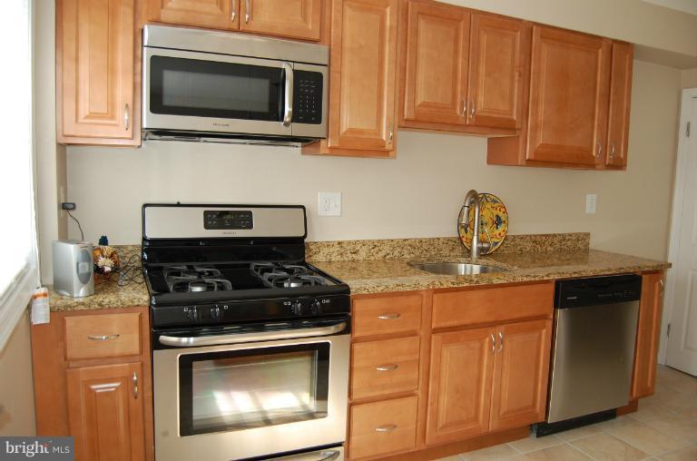 839 Reverdy Road Baltimore, MD 21212 - Photo 9 of 16 a kitchen with stainless steel appliances granite countertop white cabinets and a stove top oven