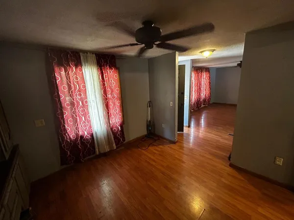 an empty room with wooden floor and windows