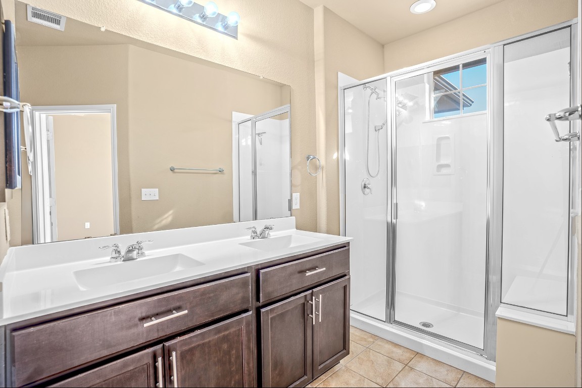 2880 Donnell Drive, Unit 2003 Round Rock, TX 78664 - Photo 22 of 27 a bathroom with a granite countertop sink a mirror and a shower