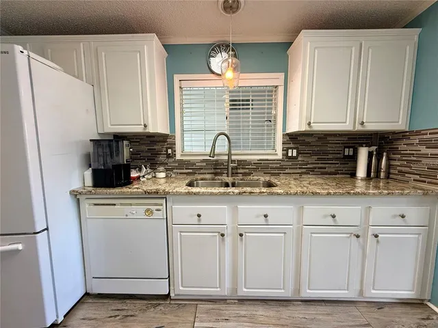 a kitchen with granite countertop white cabinets and sink