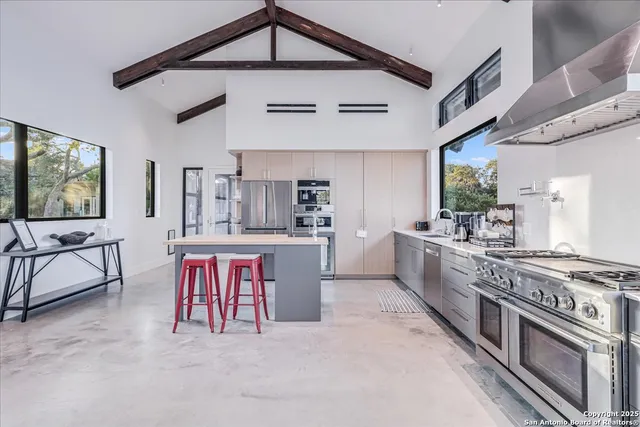 a kitchen with stainless steel appliances granite countertop a stove a sink dishwasher and white cabinets with wooden floor