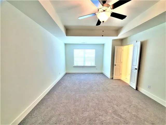 en empty room with windows and ceiling fan