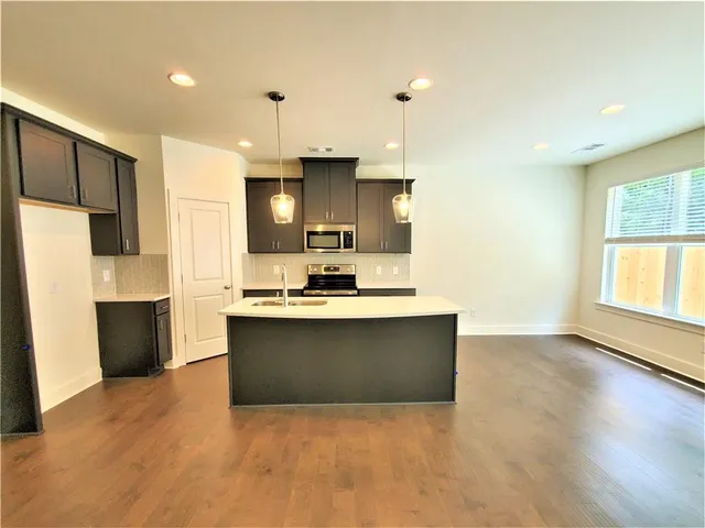 a view of kitchen with stainless steel appliances granite countertop a sink and a stove