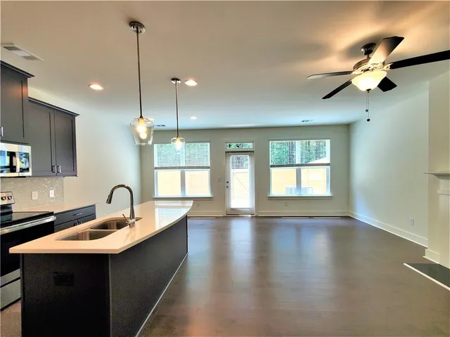 a kitchen with stainless steel appliances granite countertop a sink a window and wooden floor