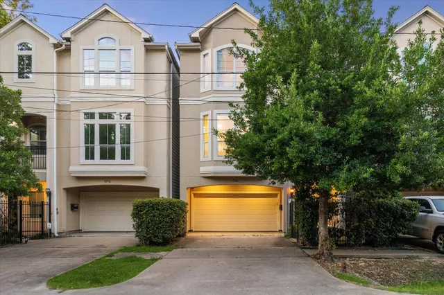 a view of a white house next to a yard with potted plants