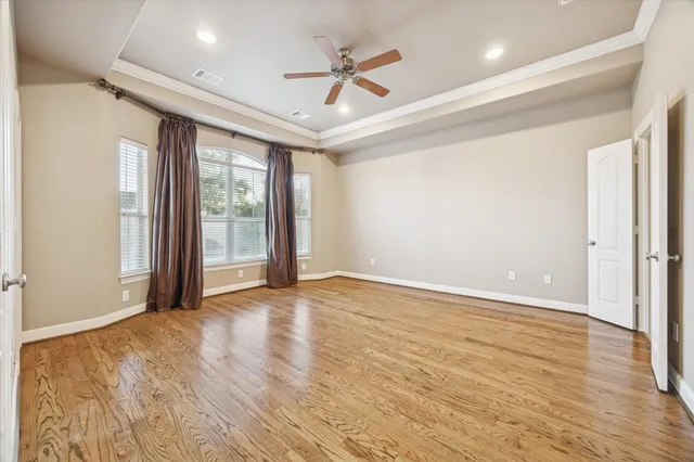 an empty room with wooden floor and ceiling fan