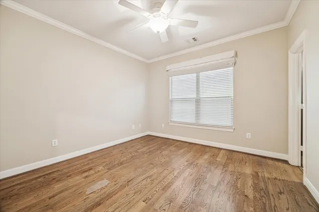 an empty room with wooden floor chandelier fan and windows