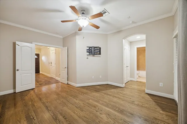 an empty room with wooden floor and a ceiling fan